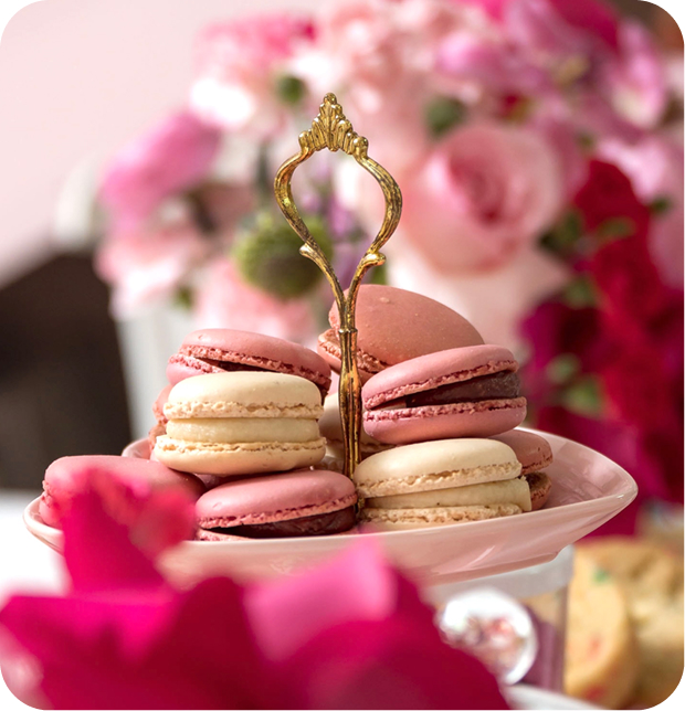 A collection of white and pink alfajores on a table decorated with several roses